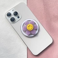 Dettaglio del supporto magnetico a fiore viola con faccina su retro di smartphone bianco - Fiore Viola con Faccia Felice