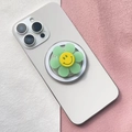 Detail of floral smiley face magnetic phone socket stand on a white smartphone - Light Green Smiley Flower