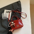 Red glossy patent leather bucket bag with silver lettering and doll pendant detail - Wine Red With Charm