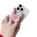 Detail of pink mother-of-pearl phone socket grip held by a hand on a white smartphone - Magnetic Stand / Pink Scallop