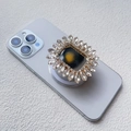 Detailansicht eines Sonnenblumen-Strass-Magnethalters auf einem lila Smartphone - Magnetischer Airbag-Stil / Weiß