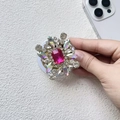 Dettaglio del supporto MagSafe di lusso con fiore di strass rosso rosa su base bianca - Strass Rosso Rosa Iridescente