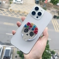 Dettaglio del supporto per telefono a teschio con rose metalliche e strass colorati - Supporto Magnetico / Teschio in Strass con Fiori