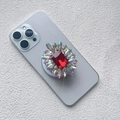 Detailed shot of a floral phone socket with a large red gemstone and aurora rhinestones - Magnetic Airbag Stand / Ruby