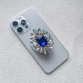 Detail shot of a luxury diamond phone socket with a large blue gem and sparkling rhinestones - Magnetic Airbag Stand / Sapphire