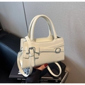Detalle del bolso blanco crema con lazo y hebilla plateada colocado sobre un libro - Blanco Roto