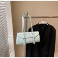 Detalle de un bolso baguette rectangular azul claro con hebillas plateadas en una percha - Azul
