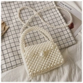 Elegante weiße Handtasche aus Perlen mit Perlenriemen auf Karomuster-Hintergrund - Weiß