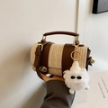 Woven straw bucket bag with brown leather trim and a plush monster charm detail - Brown
