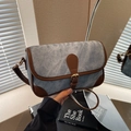 Borsa a tracolla in denim blu e pelle marrone con fibbia in metallo tenuta in mano - Blu