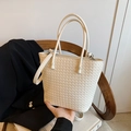 Chic white woven leather tote bag with circular handles and adjustable strap on a chair - Off White