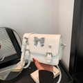 Chic white faux leather crossbody bag with silver bow hardware and strap detail - White