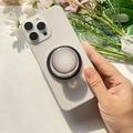 Détail d'un support MagSafe minimaliste sur coque grise avec un fond floral naturel - Support Magnétique / Dégradé Gris Noir - Couleur Unie