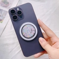 Gros plan d'un support Magsafe pailleté fixé sur un smartphone violet sur fond blanc - Support Magnétique / Confettis Colorés