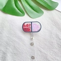 Detail of pill-shaped badge reel with heart sequins and Chill text on fabric background - Heart Sequin Pill Capsule Style (7)