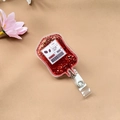 Détail macro du porte-badge sac de sang en acrylique avec paillettes rouges - Carburant énergétique