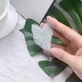 Detail of heart leaf acrylic badge reel with translucent texture held in hand - Snow White Leaf