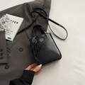 Borsa a tracolla plissettata nera lucida con ciondolo a cuore su sfondo abito grigio - Nero