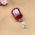 Gros plan sur l'enrouleur de badge sac de sang avec paillettes rouges et texte - Poche de sang O