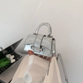 Mini silver mirror-finish handbag with metal bead chain and top handle shown in lifestyle - Silver