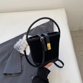 Classic black suede bucket bag with gold lock and adjustable strap on a white base - Black