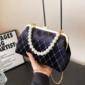 Black velvet shell bag with pearl handle and gold chain strap in a minimalist setting - Black