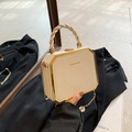 Borsa beige a scatola con finiture dorate e manico intrecciato su blazer nero - Rosa