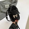 Black bucket bag featuring a silver mirror bow and drawstring closure with crossbody strap - Black