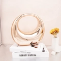 Decorazione artistica circolare oro a specchio esposta su un libro d'arte bianco - Champagne