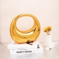Luxurious gold acrylic crescent handbag with round handle on decorative books - Gold
