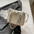 Elegante weiße Beuteltasche mit Krokostruktur und Silberkette auf weichem Bettzeug - Gebrochenes Weiß
