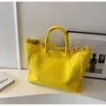 Detailed macro of yellow canvas tote bag featuring long bohemian style fringe and textures - Yellow
