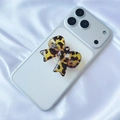 Detail of leopard print bow phone socket stand on white smartphone back with silk texture - Tortoiseshell
