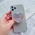 Detailed view of a heart-shaped holographic phone grip on a silver smartphone - Striped Holographic