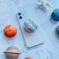 Macro view of 3D embossed planet phone grip on a white smartphone with cosmic decor - Jupiter