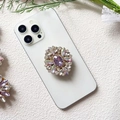 Detail view of a luxury purple crystal flower phone socket on a white mobile phone - Purple Iridescent Gem (Rhombus Rainbow Purple - Airbag Stand)
