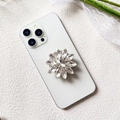 Detailed close-up of a luxury sunflower crystal phone socket on a white smartphone - Silver Sunflower Diamond (Daisy Diamond - Airbag Stand)