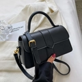 Classic black crossbody square bag with gold buckle and adjustable strap in hand - Black
