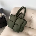Minimalist deep green quilted down tote bag with square texture on a white leather sofa - Green