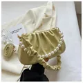 Detail der pistaziengrünen Cloud-Bag mit Perlenhenkel und weichen Lederriemen - Gelb