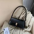Schwarze baguette schultertasche mit goldverschluss auf beige gestricktem stoff - Schwarz
