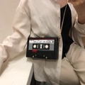 Close-up of vintage cassette-shaped crossbody bag with gold chain and music print - Black