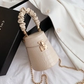 Detail of beige crocodile pattern bucket bag with golden lock and scrunchie handle - Beige
