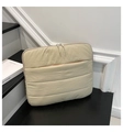 Close-up of beige quilted laptop sleeve with front pocket resting on black stairs - Khaki