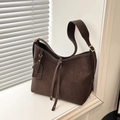 Dark brown matte suede tote bag with tie detail and golden hardware in window light - Brown