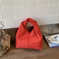 Close-up of red suede cloud bag showing soft pleated texture and decorative knot handle - Red