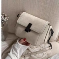 Beige textured PU leather crossbody bag with black chain strap on a soft beige sofa - White