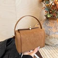 Caramel box-style handbag with lychee texture and gold clasp in a lifestyle setting - Brown