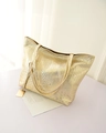 Detailopname van gouden tote bag met krokodillenreliëf en metalen merklabel - Goud