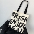 Dettaglio della borsa tote in tela con testo stampato BRISK ENJOY MEAL e manici neri - Beige